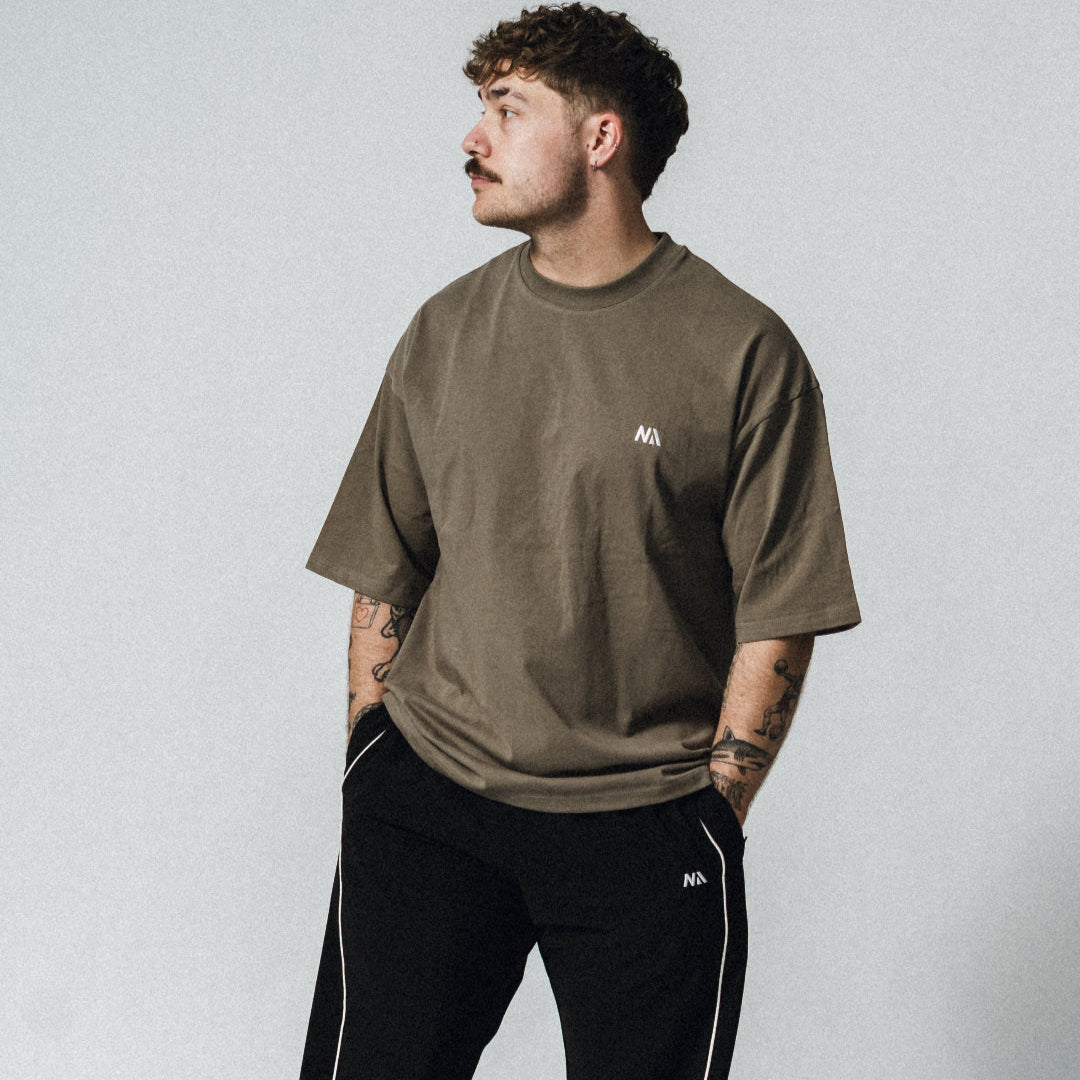 NA's Oversized t-shirt er beskrevet som det perfekte pump cover, gennemført pasform og maksimal komfort. Det bløde og åndbare bomuld kombineret med det ikoniske oversized box fit - gør den ideel som både træningstrøje og casual hverdagslook. Med drop shoulders og et naturligt fald over brystet, der skaber en flatterende silhuet, går du aldrig galt i byen med den her t-shirt.