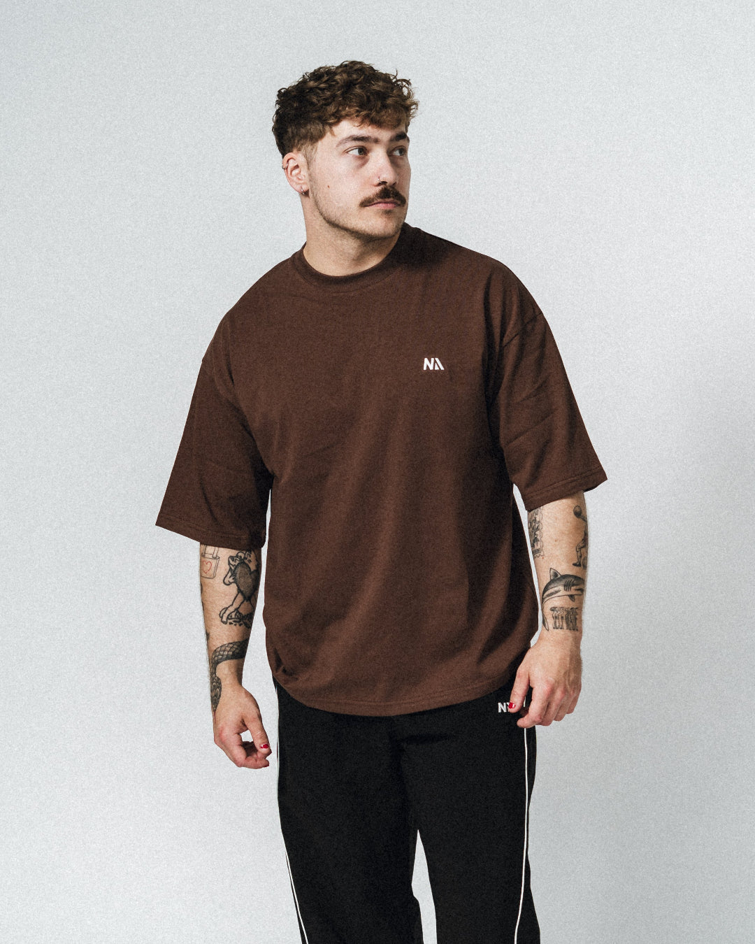 NA's Oversized t-shirt er beskrevet som det perfekte pump cover, gennemført pasform og maksimal komfort. Det bløde og åndbare bomuld kombineret med det ikoniske oversized box fit - gør den ideel som både træningstrøje og casual hverdagslook. Med drop shoulders og et naturligt fald over brystet, der skaber en flatterende silhuet, går du aldrig galt i byen med den her t-shirt.